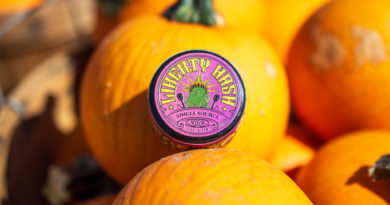 A purple jar of rosin sits on a mini pumpkin. The top label facing out says Liberty Hash.